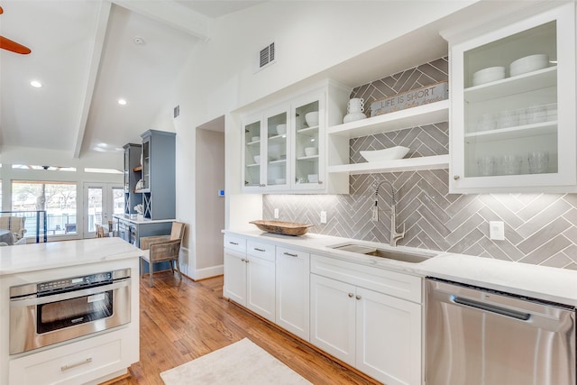 kitchen with sink, oven, white cabinetry, stainless steel dishwasher, and lofted ceiling with beams