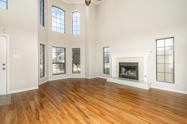 unfurnished living room with a towering ceiling, a fireplace, and light wood-type flooring