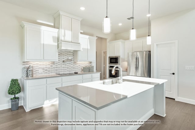 kitchen featuring decorative light fixtures, white cabinetry, backsplash, a kitchen island with sink, and appliances with stainless steel finishes