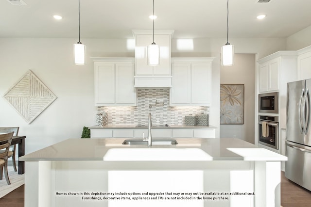 kitchen featuring stainless steel appliances, hanging light fixtures, and an island with sink