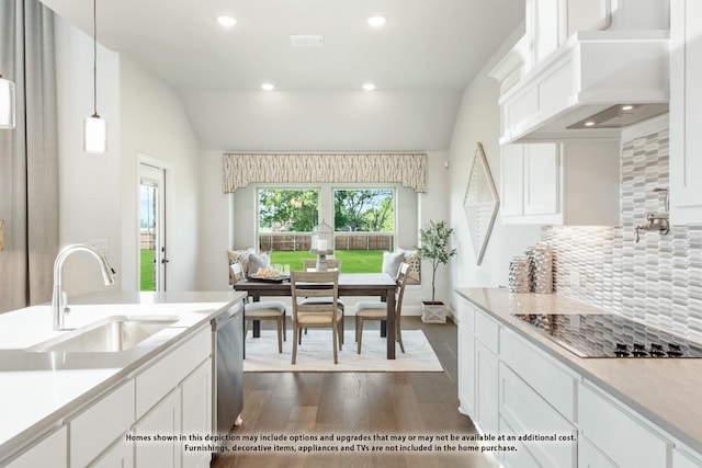 kitchen featuring hanging light fixtures, custom range hood, black electric cooktop, white cabinetry, and sink