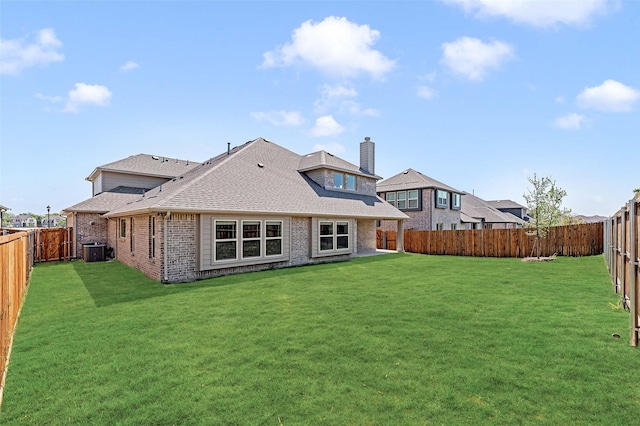 rear view of property with brick siding, a lawn, a shingled roof, and a fenced backyard