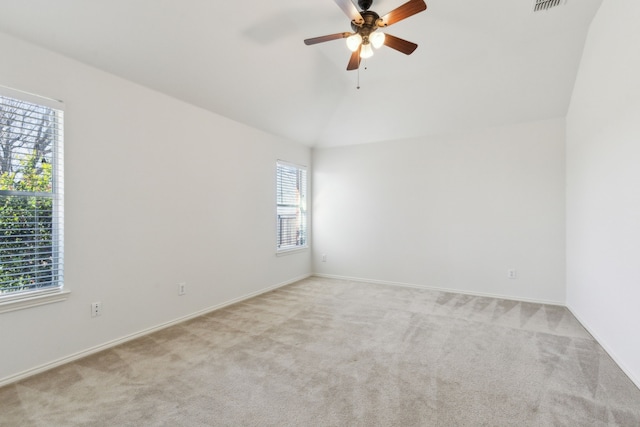 empty room with ceiling fan, vaulted ceiling, and light carpet