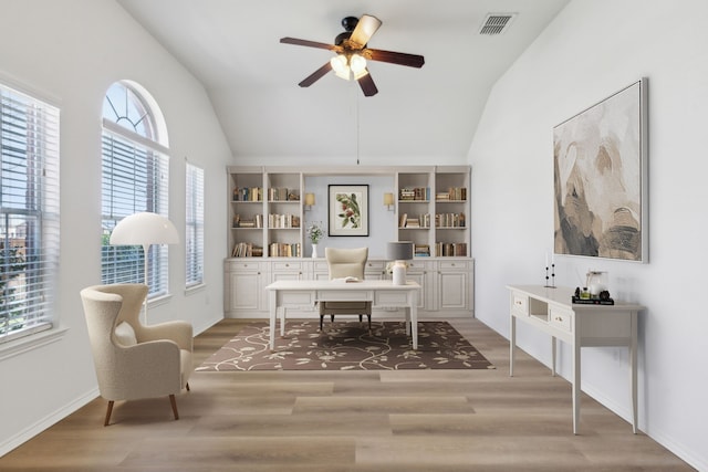 office space with vaulted ceiling, built in features, ceiling fan, and wood-type flooring