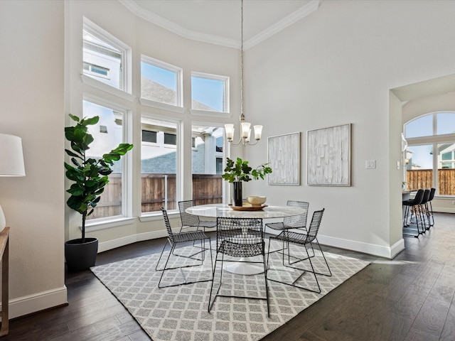 dining space with a high ceiling, dark hardwood / wood-style flooring, a chandelier, and crown molding