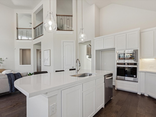 kitchen featuring white cabinetry, hanging light fixtures, high vaulted ceiling, a kitchen island with sink, and appliances with stainless steel finishes