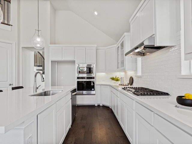 kitchen featuring hanging light fixtures, wall chimney range hood, tasteful backsplash, white cabinets, and sink