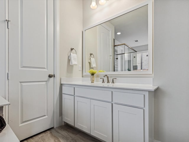 bathroom with a shower with door and vanity