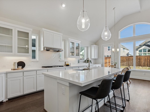 kitchen featuring lofted ceiling, a center island with sink, backsplash, and white cabinetry