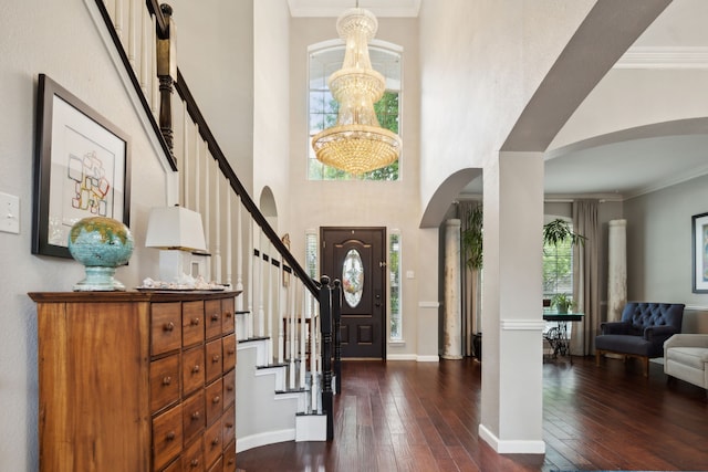 foyer with a high ceiling, dark wood-type flooring, crown molding, and a chandelier