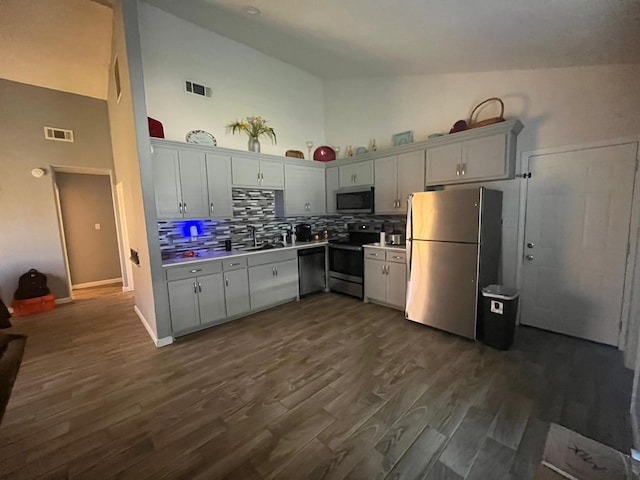 kitchen with dark hardwood / wood-style floors, stainless steel appliances, decorative backsplash, high vaulted ceiling, and sink