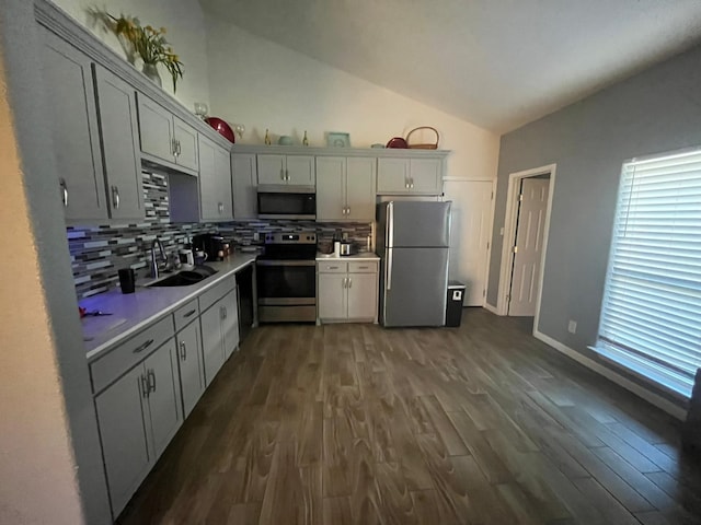 kitchen featuring sink, vaulted ceiling, backsplash, dark hardwood / wood-style flooring, and appliances with stainless steel finishes