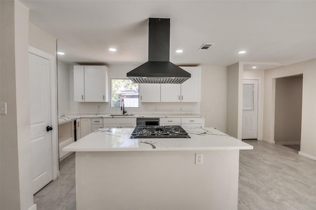 kitchen with sink, white cabinetry, island exhaust hood, light stone countertops, and a kitchen island