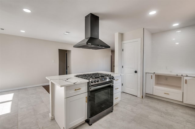 kitchen featuring light stone counters, range hood, a kitchen island, stainless steel gas stove, and white cabinets