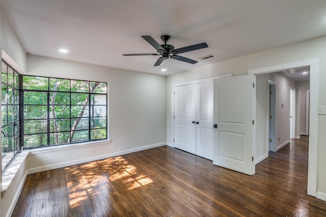 unfurnished bedroom featuring dark wood-type flooring, ceiling fan, and a closet