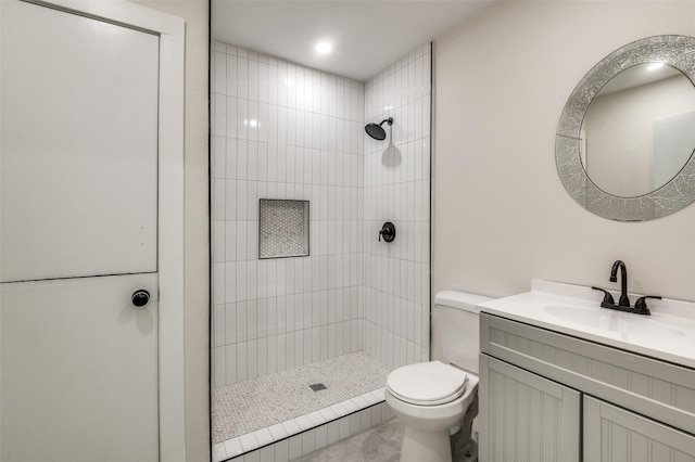 bathroom featuring tiled shower, vanity, and toilet