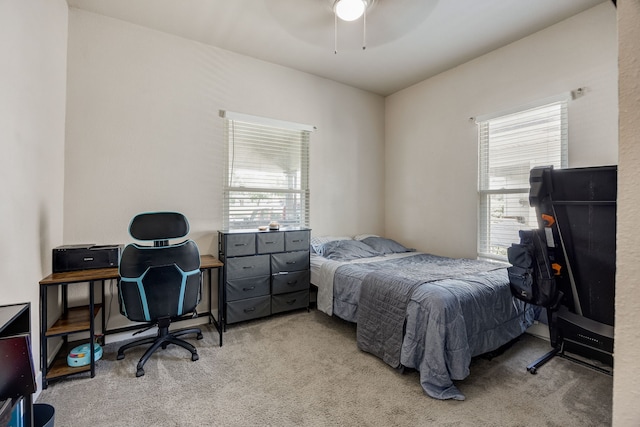 bedroom featuring light colored carpet, ceiling fan, and multiple windows