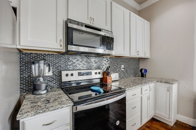 kitchen with stainless steel appliances, light stone countertops, backsplash, and white cabinetry