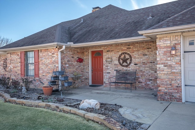 115 Juanita Ave, Wills Point, TX 75169 - property entrance with roof with shingles, brick siding, a chimney, and a patio