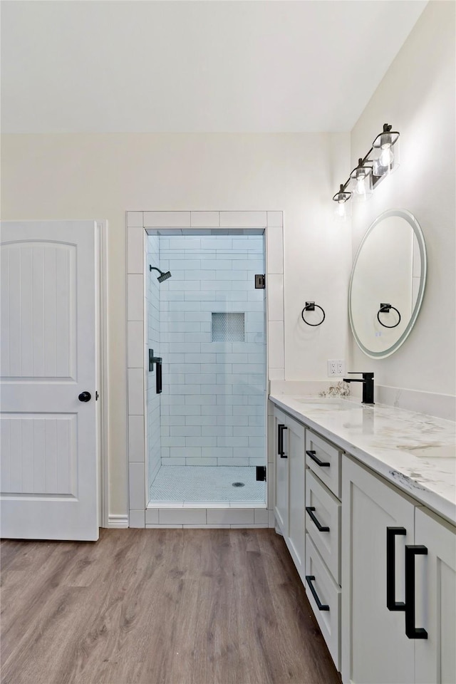 bathroom with a tile shower, vanity, and hardwood / wood-style floors