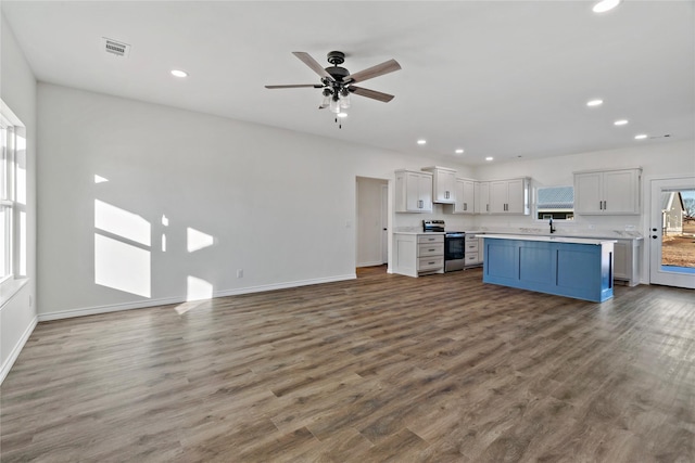 kitchen featuring white cabinets, a center island, tasteful backsplash, stainless steel electric range oven, and wood-type flooring