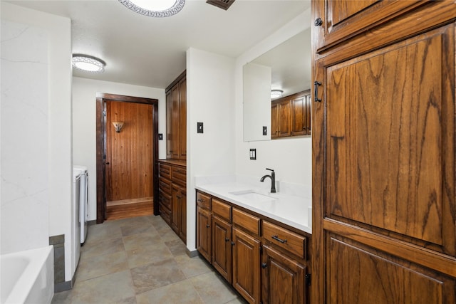 bathroom with separate washer and dryer, a bath, and vanity