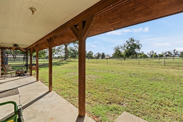 view of yard featuring an outdoor fire pit, ceiling fan, a rural view, and a patio area