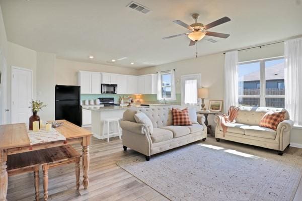 living room featuring ceiling fan and light hardwood / wood-style floors