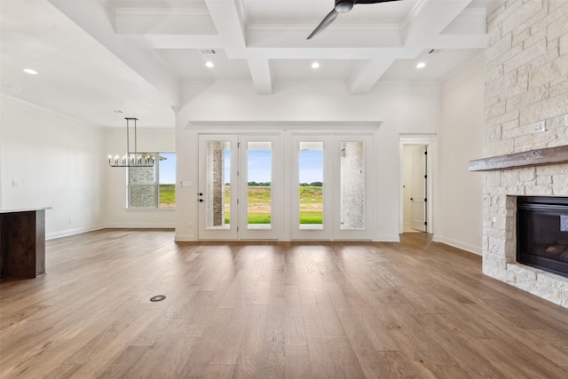 unfurnished living room featuring beam ceiling, a stone fireplace, wood finished floors, coffered ceiling, and baseboards