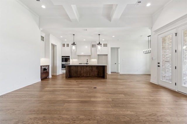 unfurnished living room with ornamental molding, visible vents, beamed ceiling, and wood finished floors