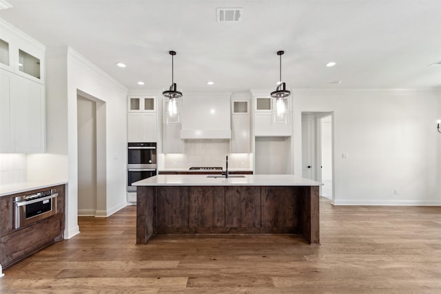 kitchen featuring visible vents, light countertops, light wood-style flooring, stainless steel double oven, and a sink