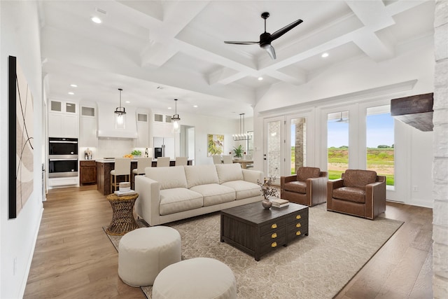 living area with light wood-style floors, coffered ceiling, beamed ceiling, and a ceiling fan