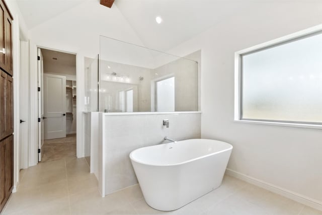 full bath featuring a walk in shower, lofted ceiling, a freestanding tub, tile patterned flooring, and a walk in closet