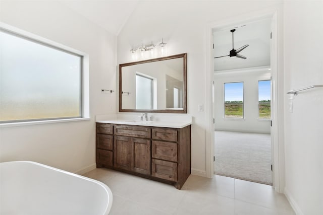 bathroom featuring a freestanding bath, vaulted ceiling, vanity, tile patterned flooring, and baseboards