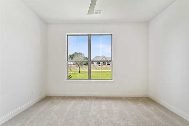 spare room featuring light carpet, ceiling fan, visible vents, and baseboards