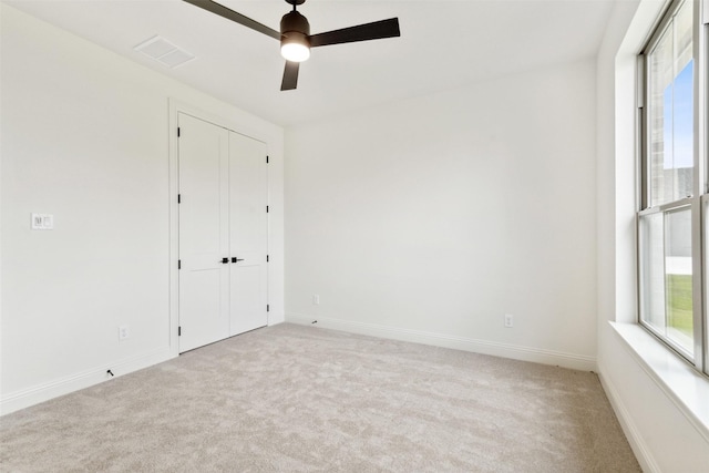 empty room featuring a healthy amount of sunlight, baseboards, light carpet, and visible vents