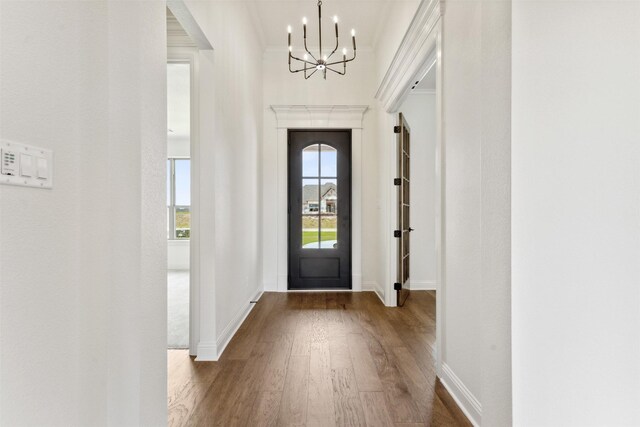 entrance foyer featuring a chandelier, ornamental molding, baseboards, and wood finished floors