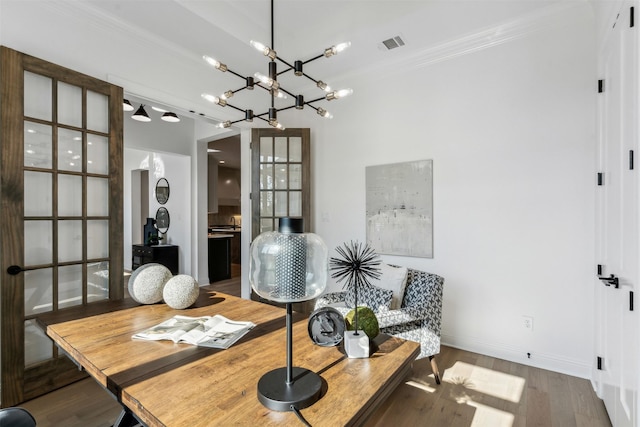 dining space with crown molding, a chandelier, and hardwood / wood-style flooring