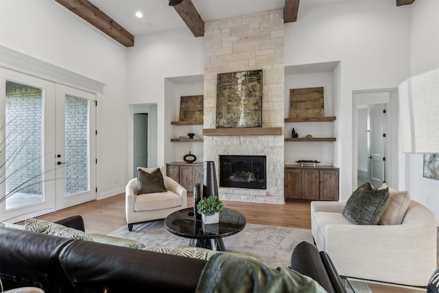 living room featuring light hardwood / wood-style floors, french doors, a fireplace, and beam ceiling