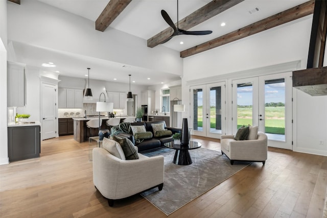 living room featuring french doors, ceiling fan, light hardwood / wood-style floors, and beamed ceiling