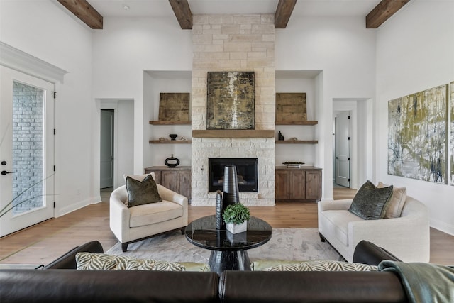 living room featuring a fireplace, light wood-type flooring, and beamed ceiling