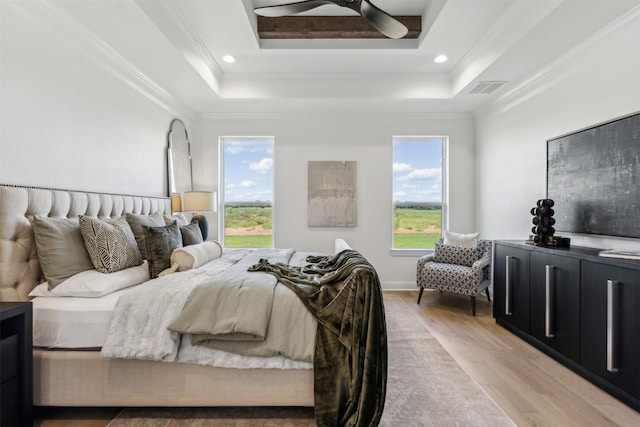 bedroom with crown molding, a raised ceiling, ceiling fan, and light hardwood / wood-style flooring