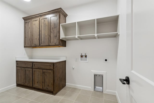 laundry room featuring electric dryer hookup, washer hookup, cabinets, light tile patterned floors, and gas dryer hookup