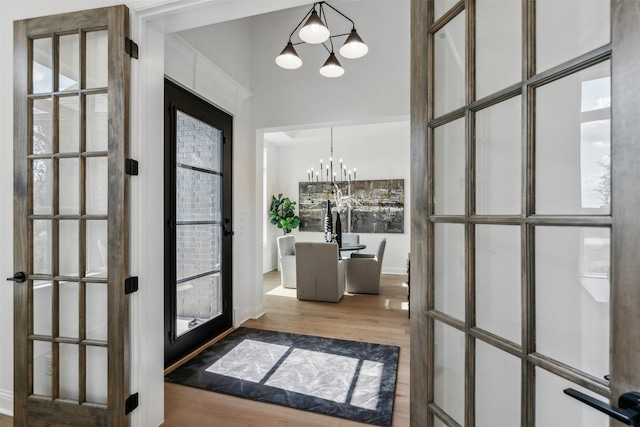 foyer entrance featuring french doors, wood-type flooring, and a notable chandelier