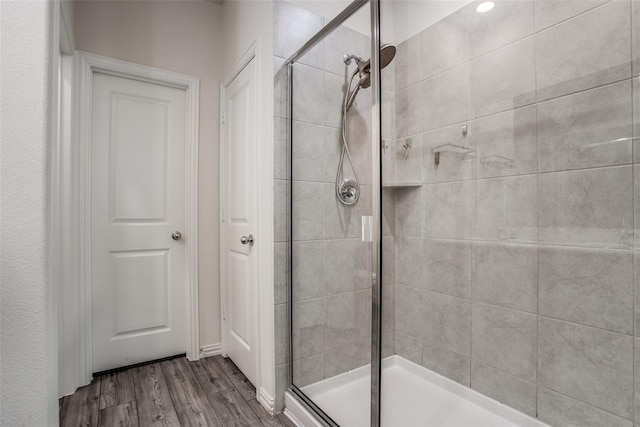 bathroom featuring a shower with shower door and wood-type flooring