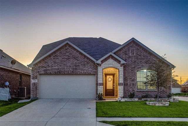 view of front of home featuring cooling unit, a yard, and a garage