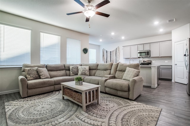 living room featuring ceiling fan and dark wood-type flooring