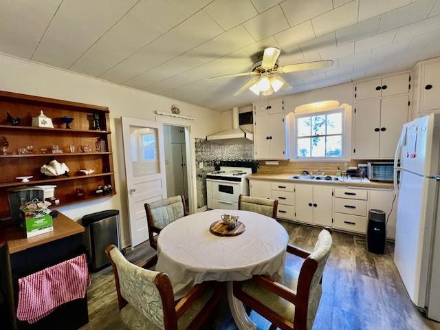 kitchen with white appliances, white cabinets, extractor fan, and backsplash