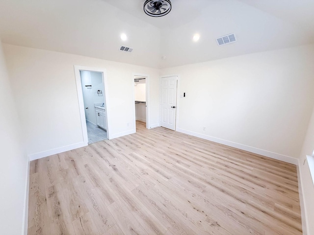 unfurnished bedroom featuring a walk in closet, light hardwood / wood-style flooring, and ensuite bathroom