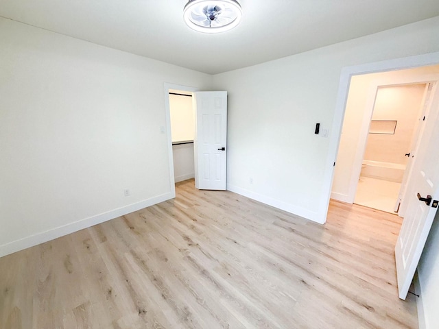 unfurnished bedroom with a walk in closet and light wood-type flooring